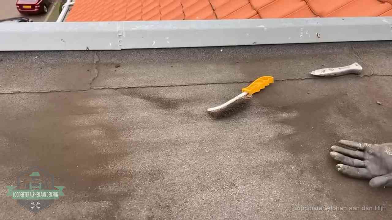 Kosten van daklekkage-reparatie in Alphen aan den Rijn Dakdekker bereidt een bitumen plat dak voor op reparatie bij de daktrim in Alphen aan den Rijn