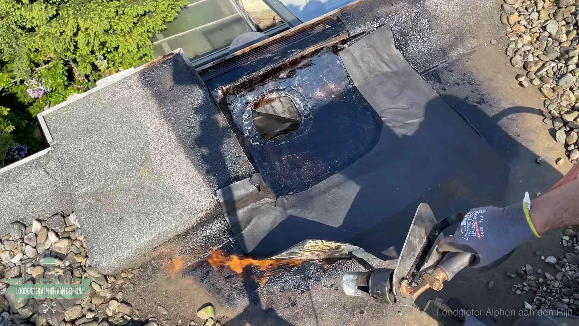 Daklekkage repareren in Alphen aan den Rijn Dakdekker brandt bitumen rond een doorvoer tijdens een daklekkage-reparatie in Alphen aan den Rijn