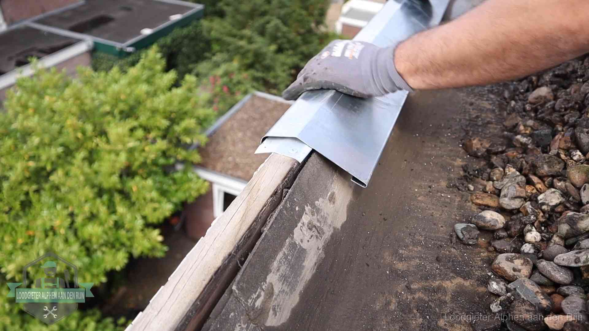 Daklekkage per wijk in Alphen aan den Rijn Dakdekker plaatst een zinken deklijst op een dakrand met uitzicht over een woonwijk in Alphen aan den Rijn
