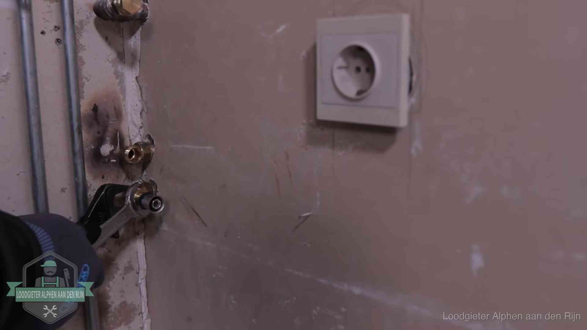 Monteur draait een perskoppeling vast op een leidingaansluiting in Alphen aan den Rijn