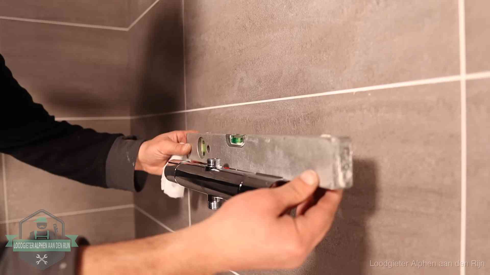 Loodgieter lijnt een douchekraan uit met een waterpas in een woning in Alphen aan den Rijn