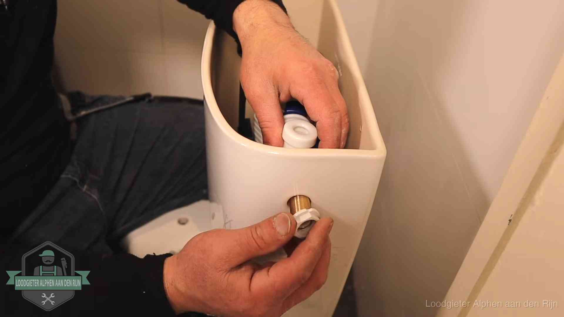 Loodgieter monteert de vlotterkraan van een stortbak bij een toilet in Alphen aan den Rijn