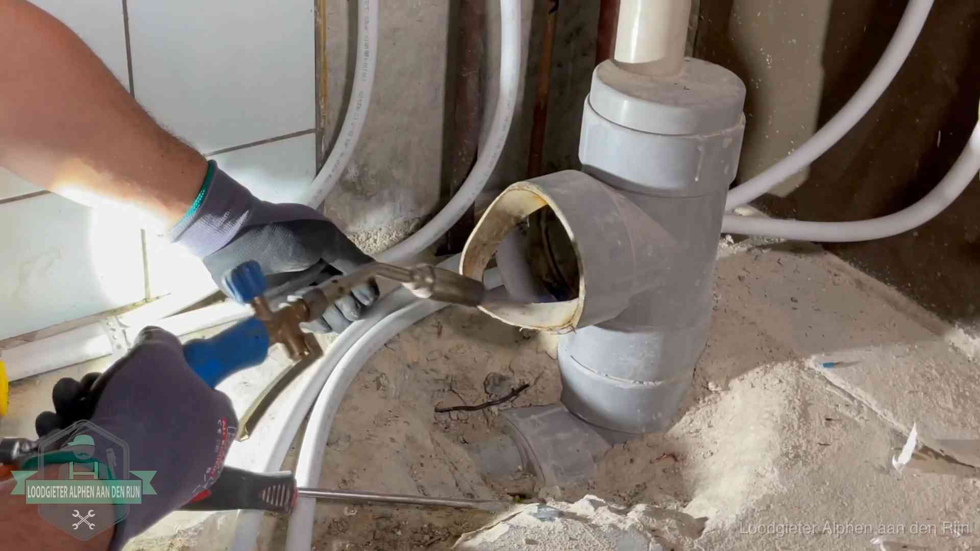 Loodgieter werkt met brander en messing kraanwerk aan leidingen in Alphen aan den Rijn