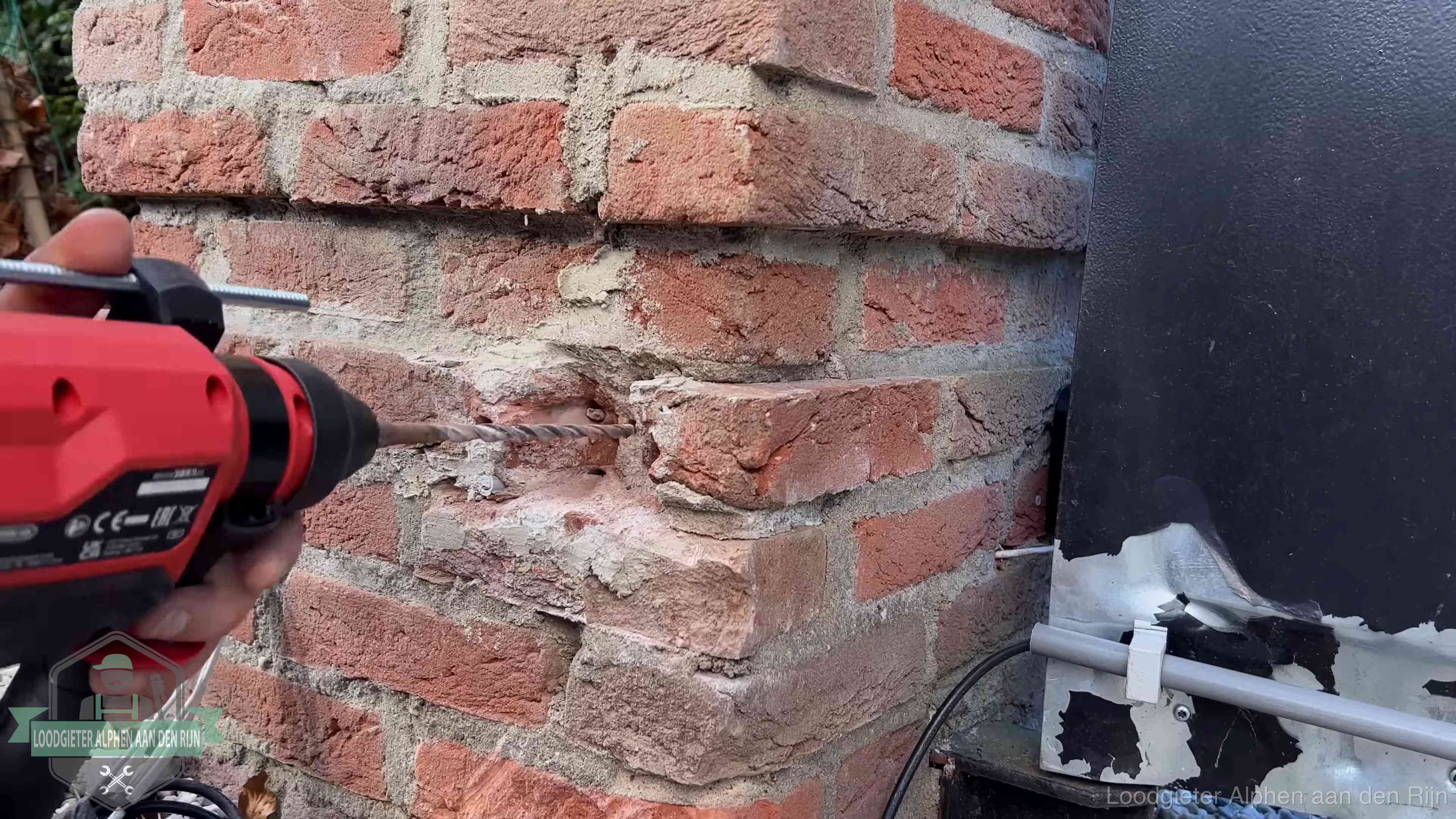 Vakman boort in de buitenmuur van een woning in de regio Alphen aan den Rijn