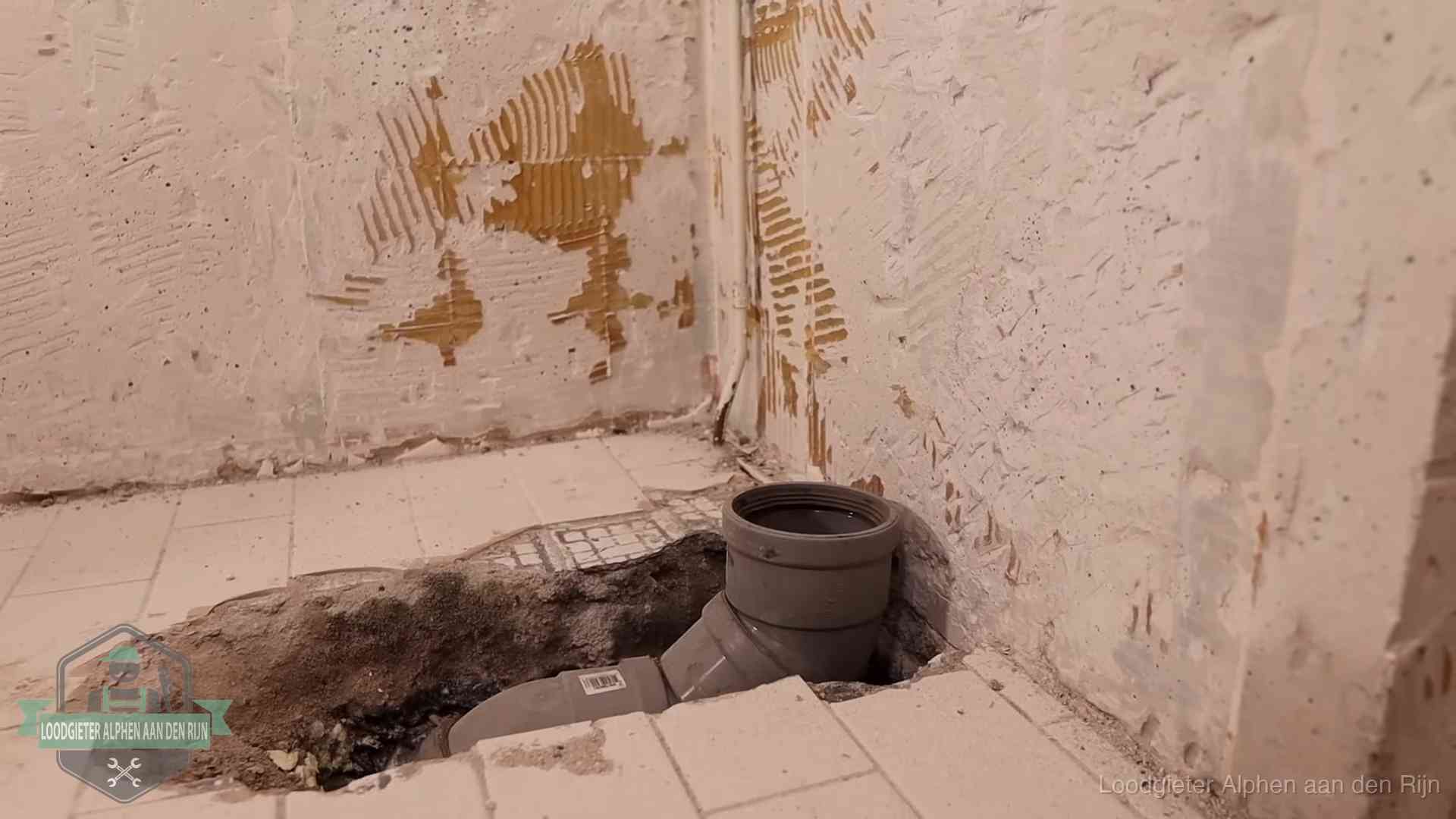 Verzakt riool herstellen in Alphen aan den Rijn Opengebroken vloer met een nieuwe pvc-rioolbocht in een gegraven sleuf in Alphen aan den Rijn