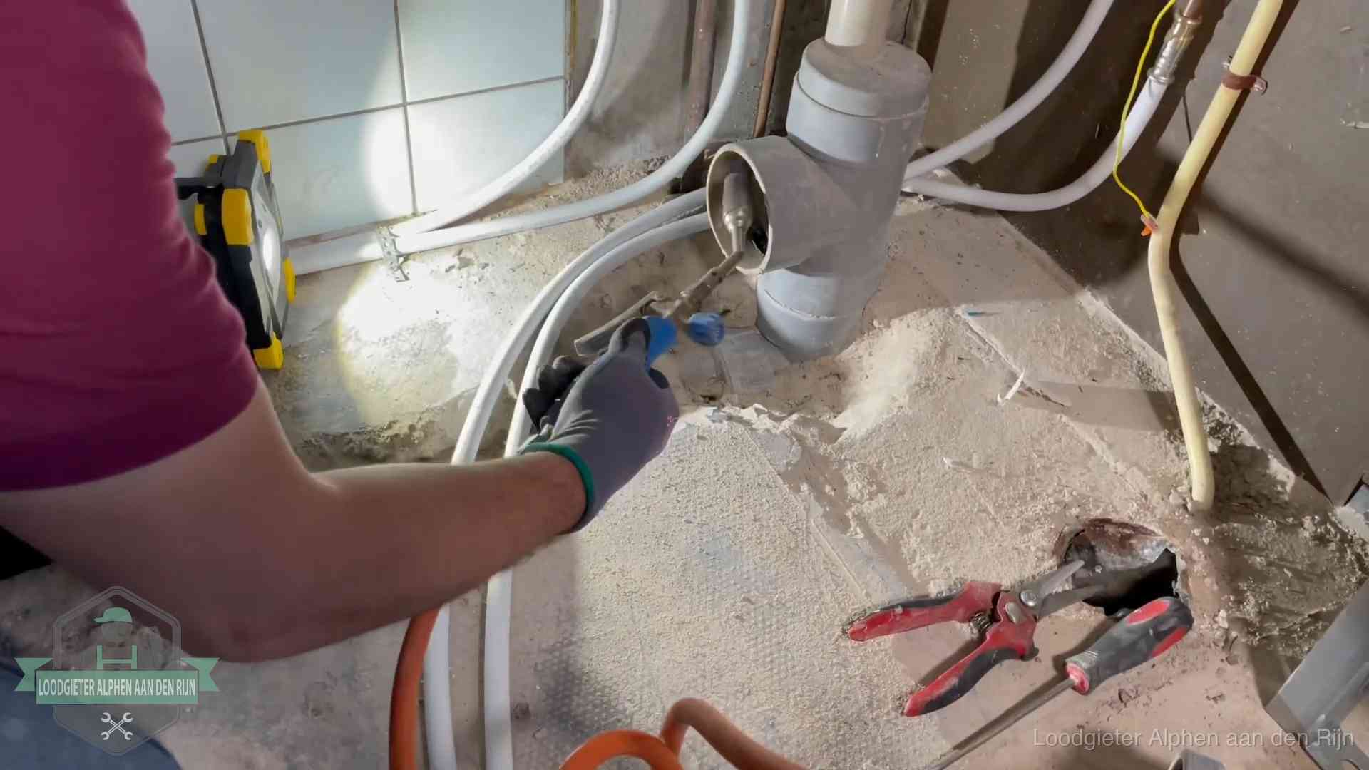 Loodgieter werkt aan leidingen bij een pvc-standleiding in een appartement in Alphen aan den Rijn