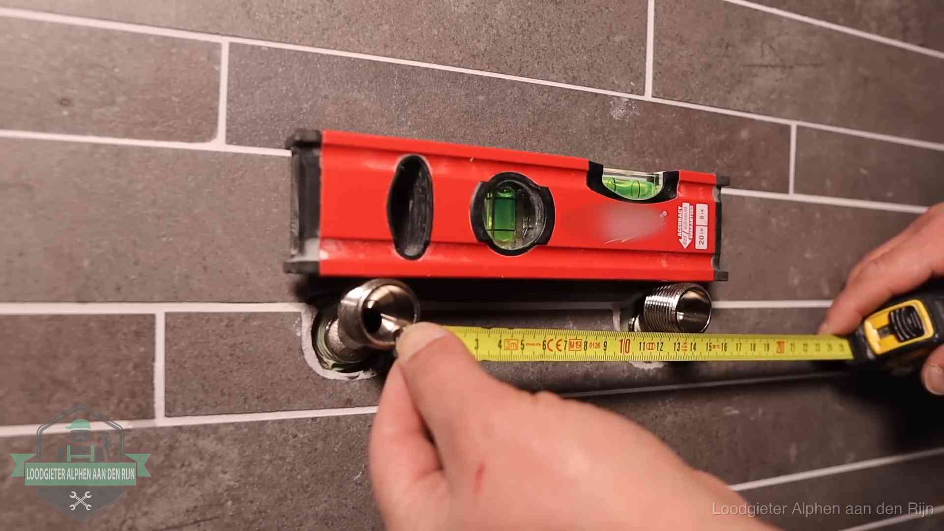 Waterpas en duimstok bij kraan-aansluitpunten in een badkamer in Alphen aan den Rijn