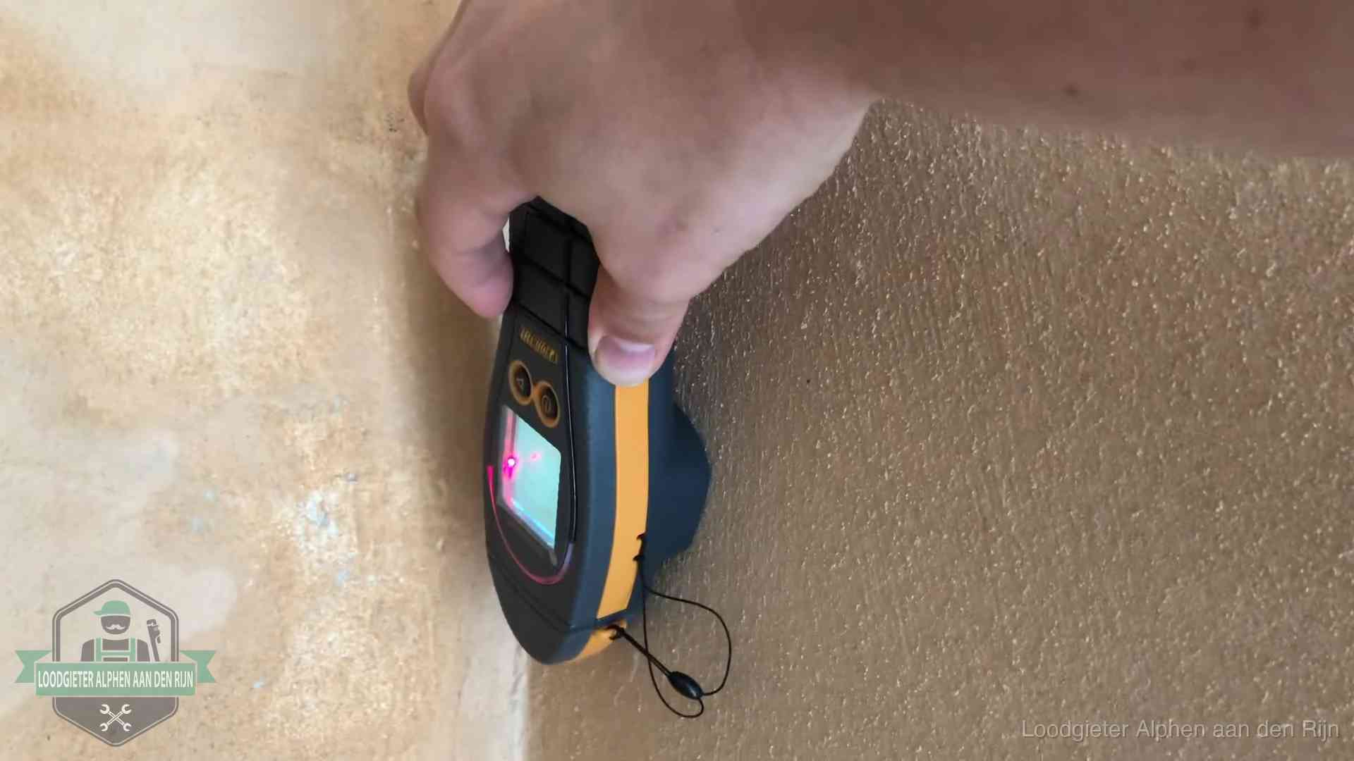Daklekkage opsporen zonder hakwerk in Alphen aan den Rijn Vochtmeter tegen een muur met vochtplekken tijdens het opsporen van een daklekkage in Alphen aan den Rijn
