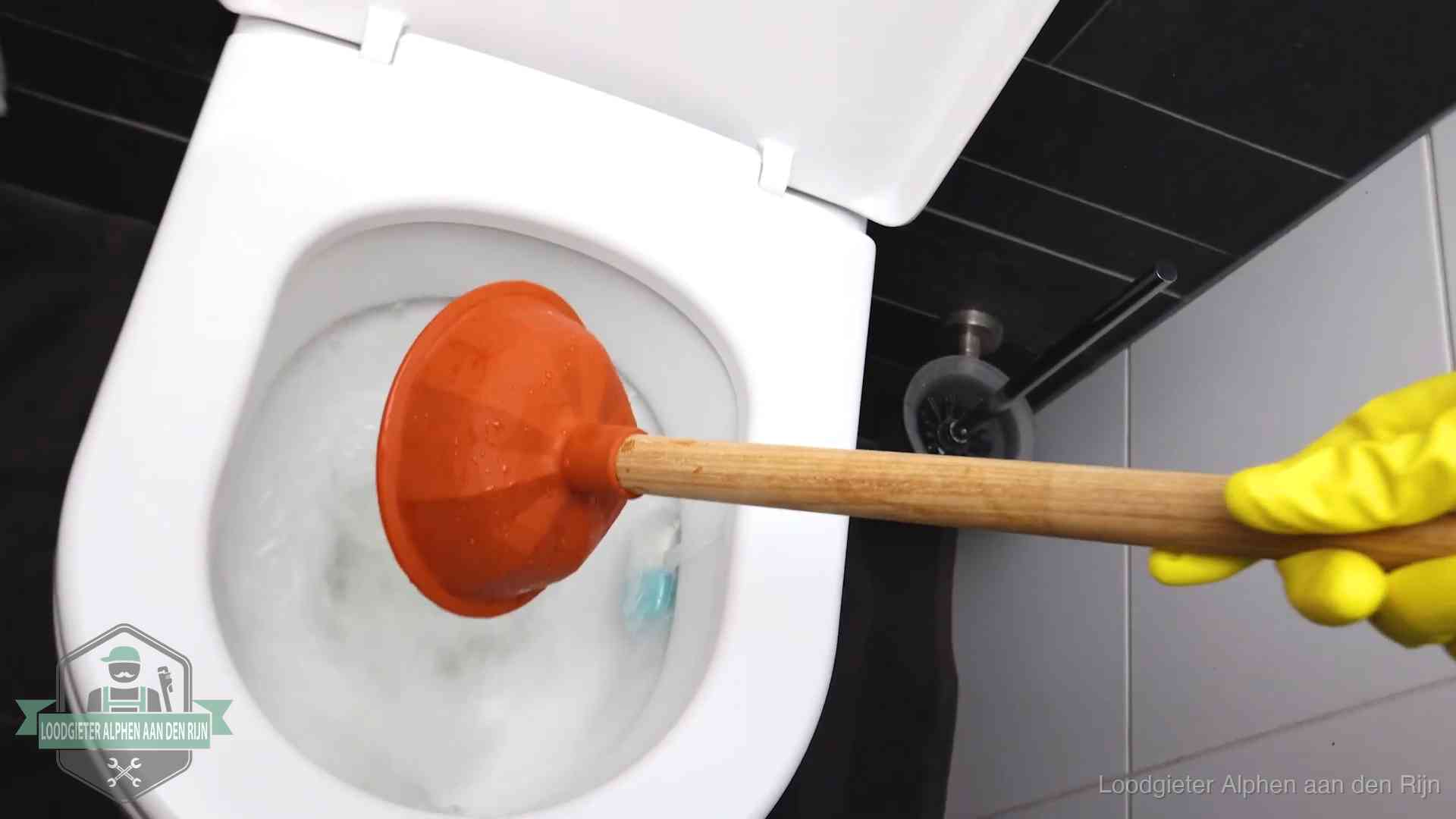 Plopper wordt in de wc-pot gedrukt bij het ontstoppen van een toilet in Alphen aan den Rijn