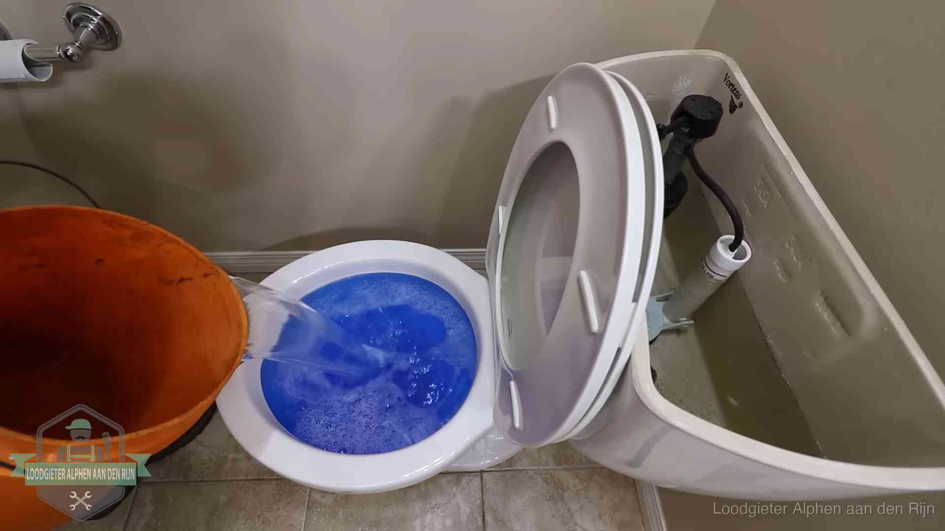 Water bij de wc-pot wordt met een emmer weggewerkt om schade te beperken in Alphen aan den Rijn